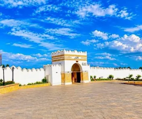 The white city gate of Harar with its crenellated wall under a bright blue sky