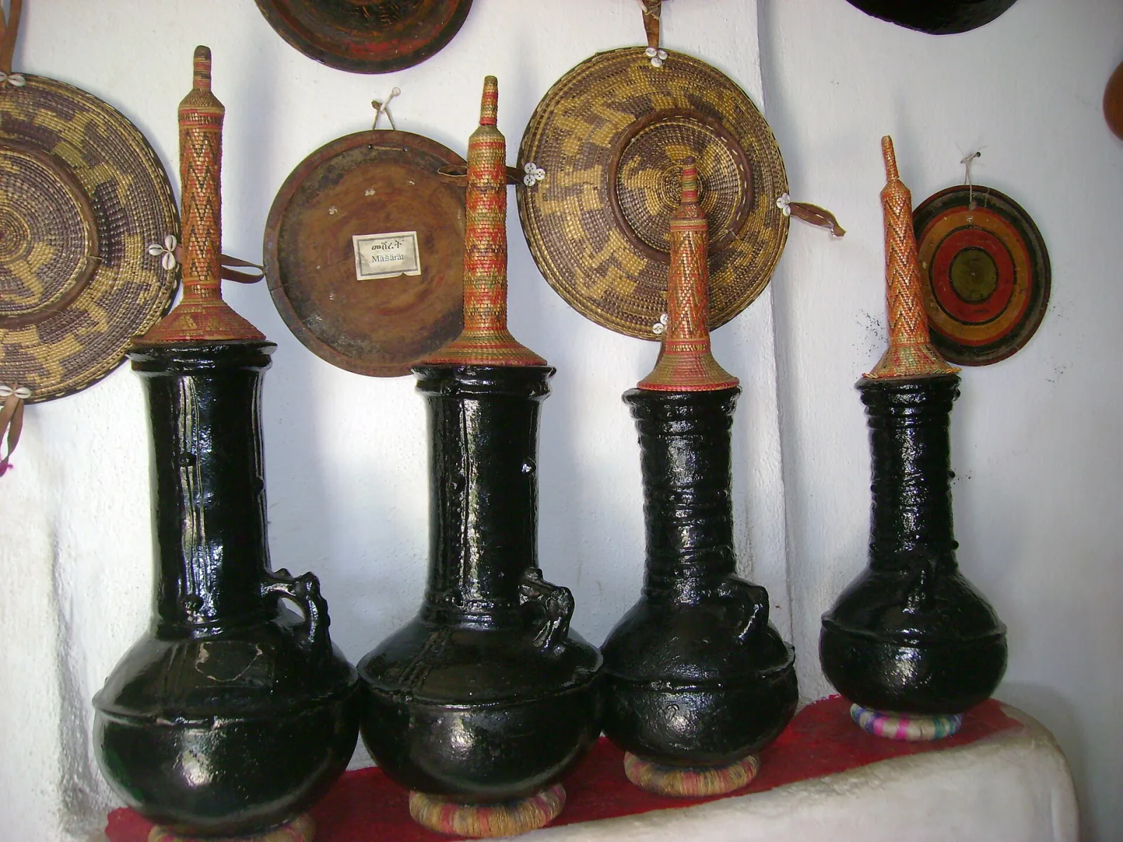 Black clay coffee pots in front of woven baskets in a Harari home