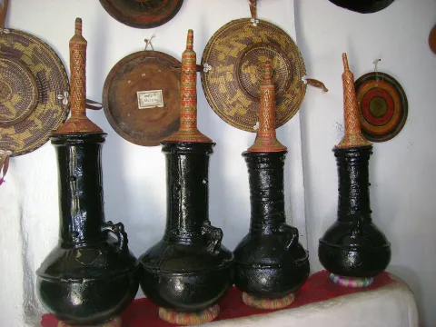 Black clay coffee pots in front of woven baskets in a Harari home